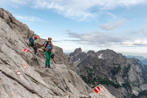 Female mountaineers on marked route through rocky alpine terrain