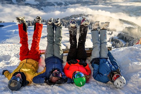 Skiers lie in the snow and stretch their legs in the air
