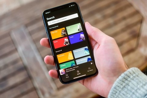 Hand holds iPhone 11 with Spotify App on display