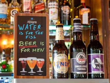 Different beer bottles and funny sign in a bar