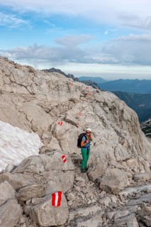 Mountaineer on marked route through rocky alpine terrain