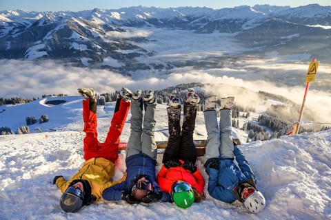 Skiers lie in the snow and stretch their legs in the air