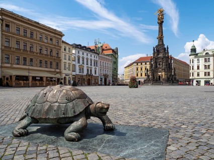 Sculpture of a turtle on the Oberring square with Unesco World Heritage Column of the Trinity