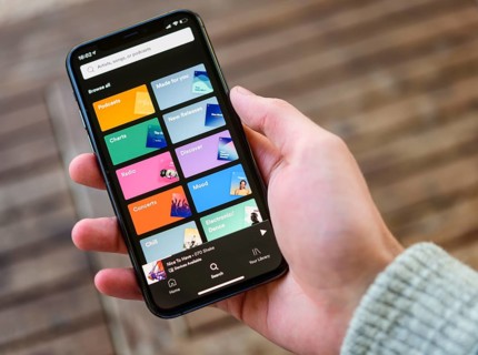 Hand holds iPhone 11 with Spotify App on display