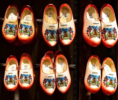 Colourfully painted traditional Dutch wooden shoes hanging on a wooden wall