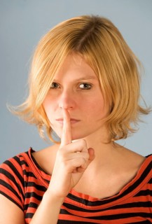 Teenager holds index finger to mouth