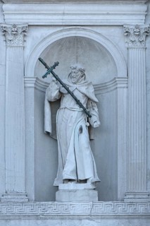 Sculpture of a saint with cross in a wall niche