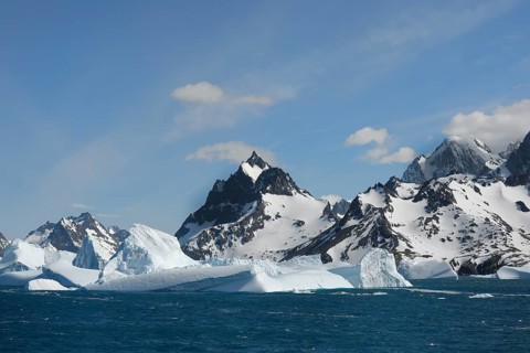 Floating icebergs off mountain peaks with snow