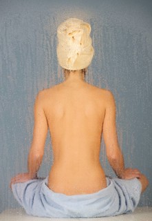 Woman sitting in a steam bath behind glass pane with drops of water, 24 years