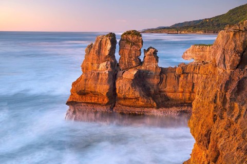 Rock formations on the coast of Paparoa National Park in red evening sun, Punakaiki