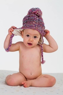 Little girl, baby with a bonnet sitting naked on a white blanket