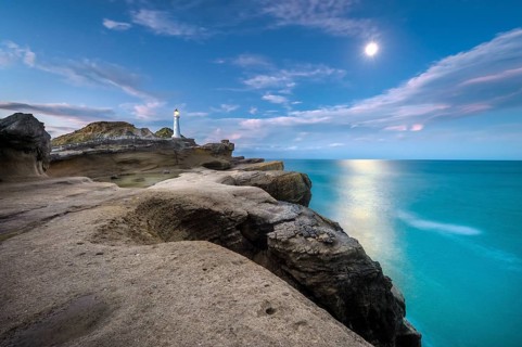 Lighthouse at full moon on the cliffs of lava rock at Castlepoint, Masterton