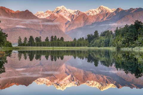 Snowy mountain peaks of Mount Cook and Mount Tasman reflected in Lake Matheson in the evening light, Westland National Park