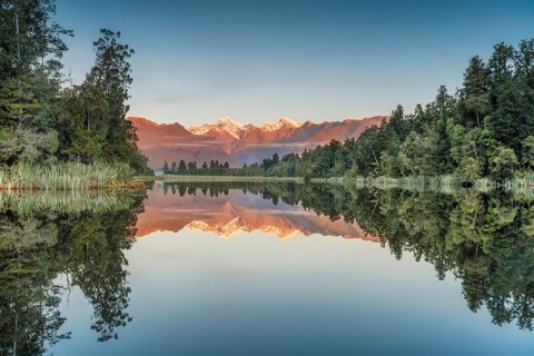 Snowy mountain peaks of Mount Cook and Mount Tasman reflected in Lake Matheson in the evening light, Westland National Park