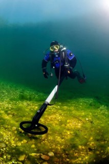 Diver in dry suit with metal detector searches the lake bottom for metal objects, Echinger Weiher