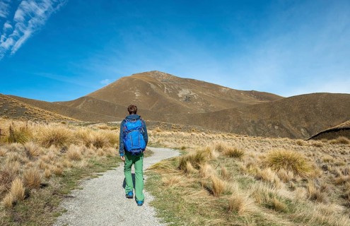 Hiker on hiking trail in barren mountain landscape, Lindis Pass