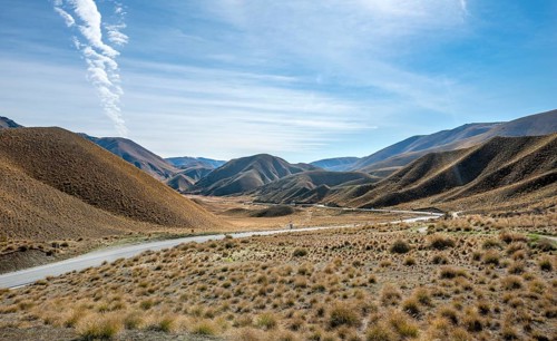 Barren mountain landscape with tufts of grass, pass road