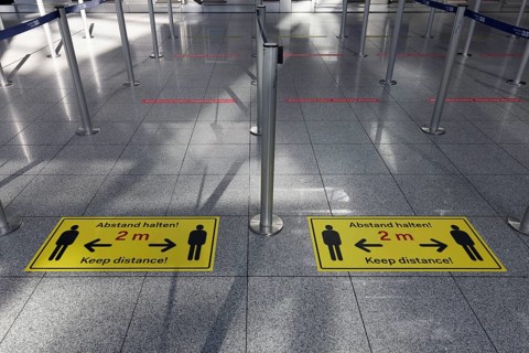 Signs with distance rule in front of the deserted baggage check, flight ban due to corona pandemic