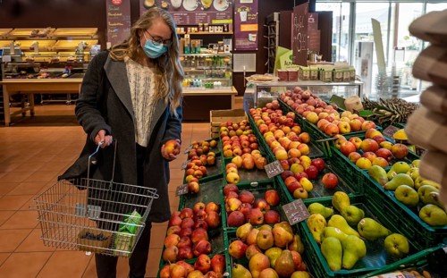 Young woman shopping in a supermarket with face mask, corona crisis