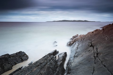 Stormy atmosphere at the rocky beach, view of Taransay Island