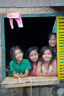 Happy children looking out of the window of their house