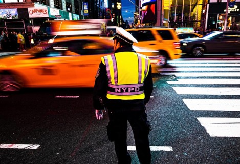 Policeman with NYPD vest monitors heavy taxi traffic in Times Square