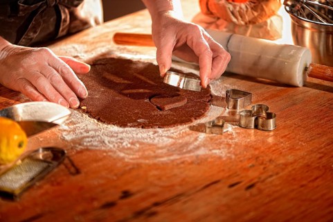 Women's hands pricking cookies from rolled out dough