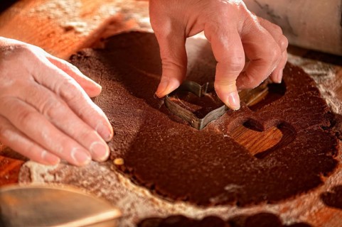 Women's hands pricking cookies from rolled out dough
