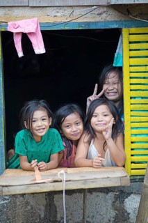 Happy children looking out of the window of their house