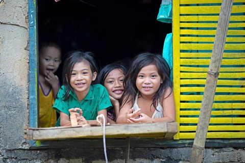 Happy children looking out of the window of their house