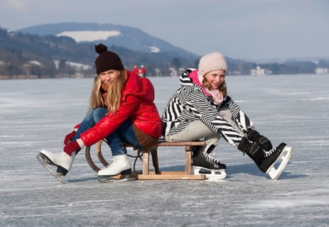 Young happy girls ice skating at a lake