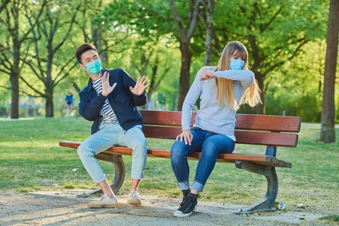 Man and woman wearing a face mask on a park bench in a municipal park
