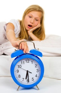 Girl in bed yawns when the alarm clock rings