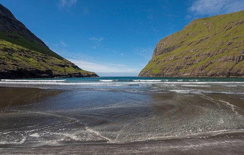 Sandy beach beach in bay surrounded by steep mountains