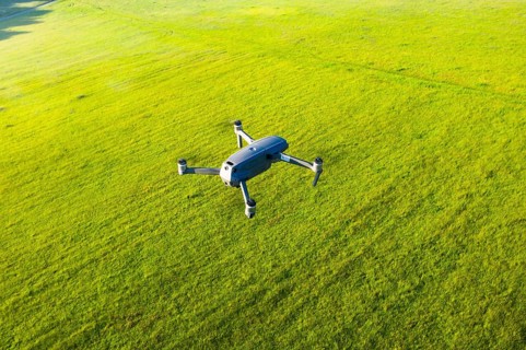 Flying drone DJI Mavic 2 Pro from above over meadow