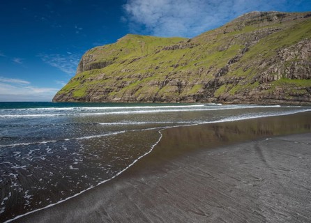 Sandy beach beach in bay surrounded by steep mountains