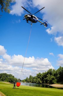 Police helicopter Airbus H 145 during exercise with fire water tank BAMBI BUCKET