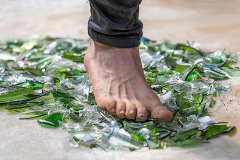 Fakir with foot walking over broken glass