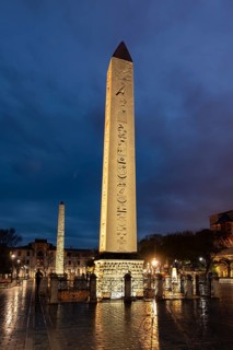 Illuminated Egyptian obelisk and brick obelisk on the Hippodrome in the evening