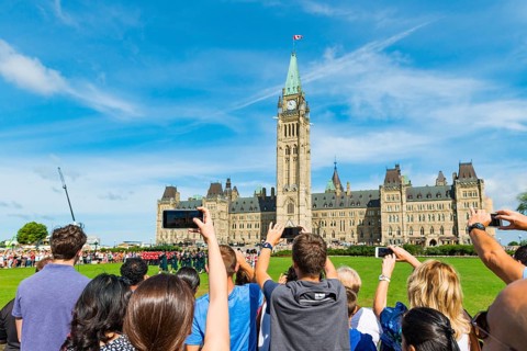 Visitors photograph the changing of the guard in front of the Canadian Parliament Building Centre Block