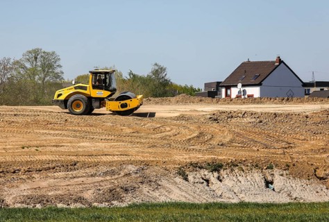 A road roller compacts the dam above the elevated sewer in the construction site