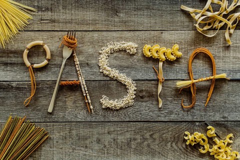 Word pasta from different noodles on wooden table