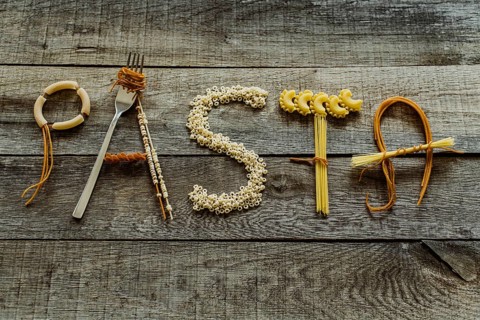 Word pasta from different noodles on wooden table