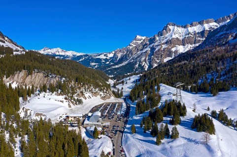 Car park and valley station of the Glacier 3000 aerial cableway to the Glacier des Diablerets ski area on the Col du Pillon mountain pass in winter