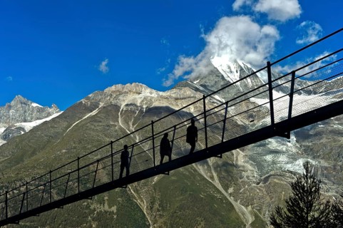 Hikers in the back light on the Charles Kuonen suspension bridge