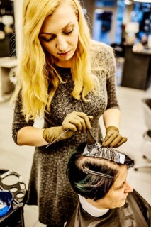 Hairdresser in a hairdressing salon dying strands of hair with aluminium foil