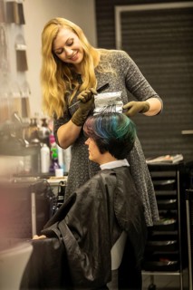 Hairdresser in a hairdressing salon dying strands of hair with aluminium foil