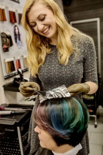 Hairdresser in a hairdressing salon dying strands of hair with aluminium foil