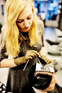 Hairdresser in a hairdressing salon dying strands of hair with aluminium foil