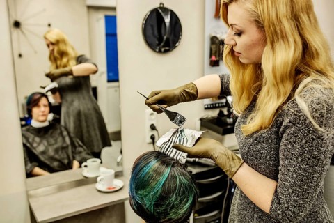 Hairdresser in a hairdressing salon dying strands of hair with aluminium foil